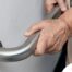 An older adult uses a grab bar representing one of the home modifications that is helpful for fall prevention for elderly adults.